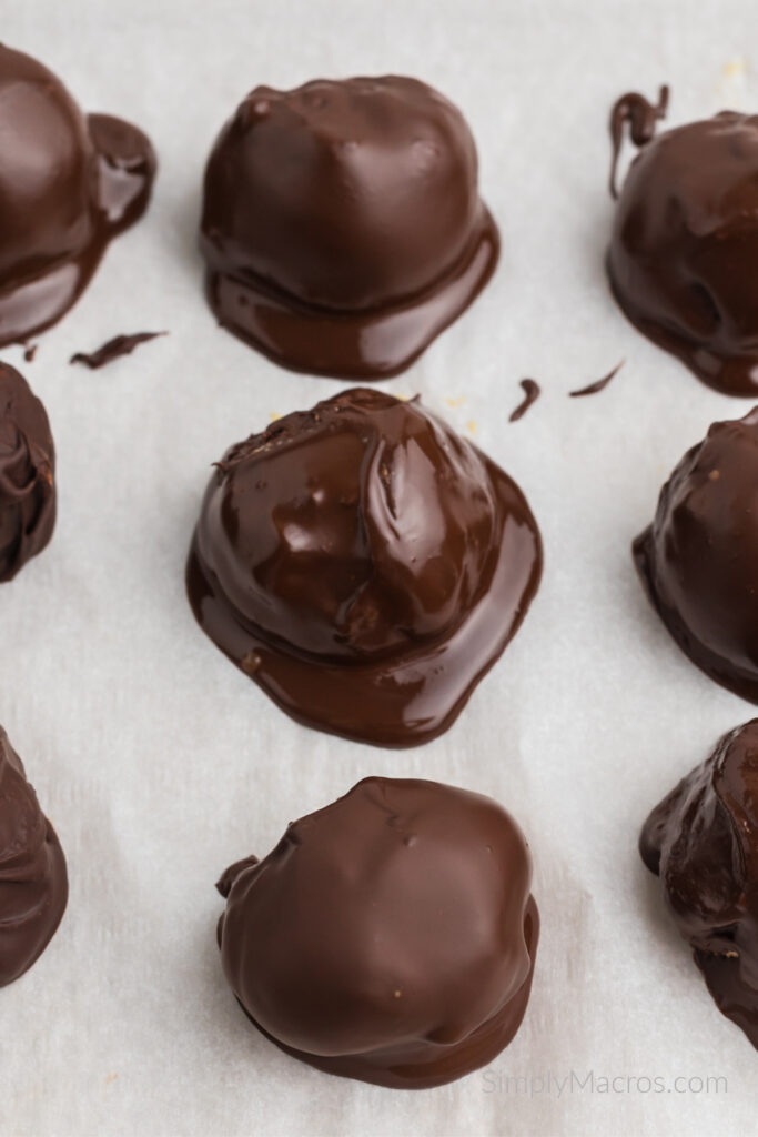 Chocolate covered peanut butter protein balls on parchment paper. 