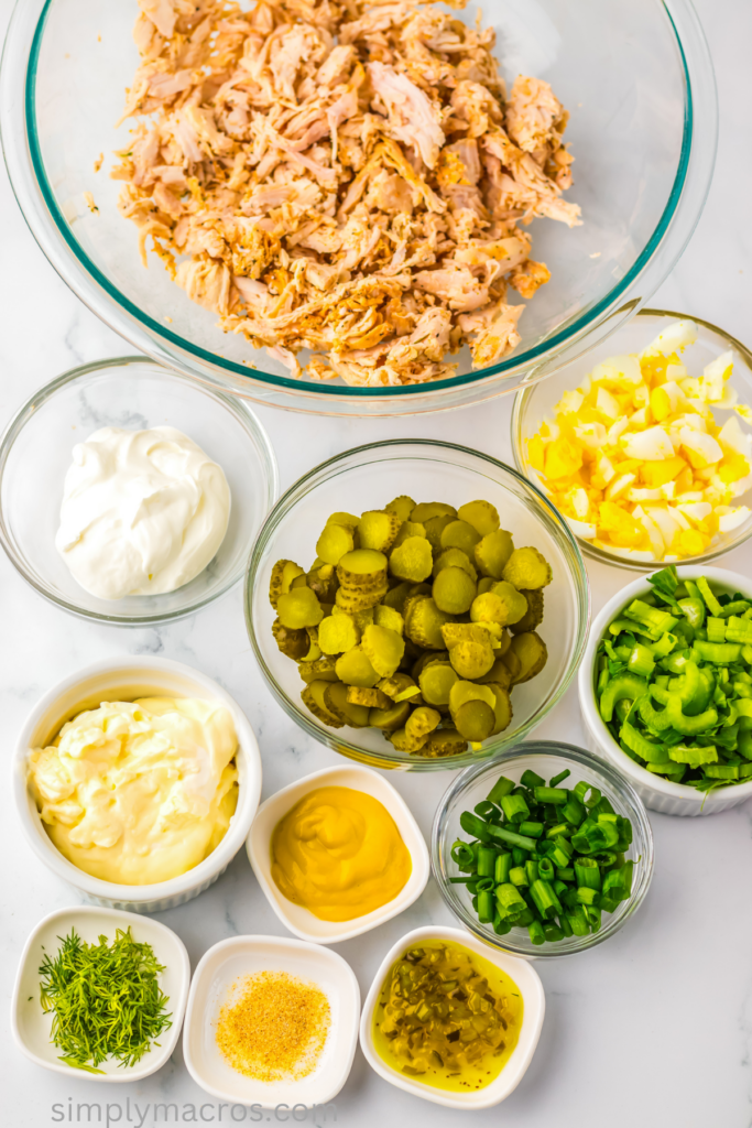 Ingredients needed to make chicken salad with dill pickles in bowls, ready to combine. 
