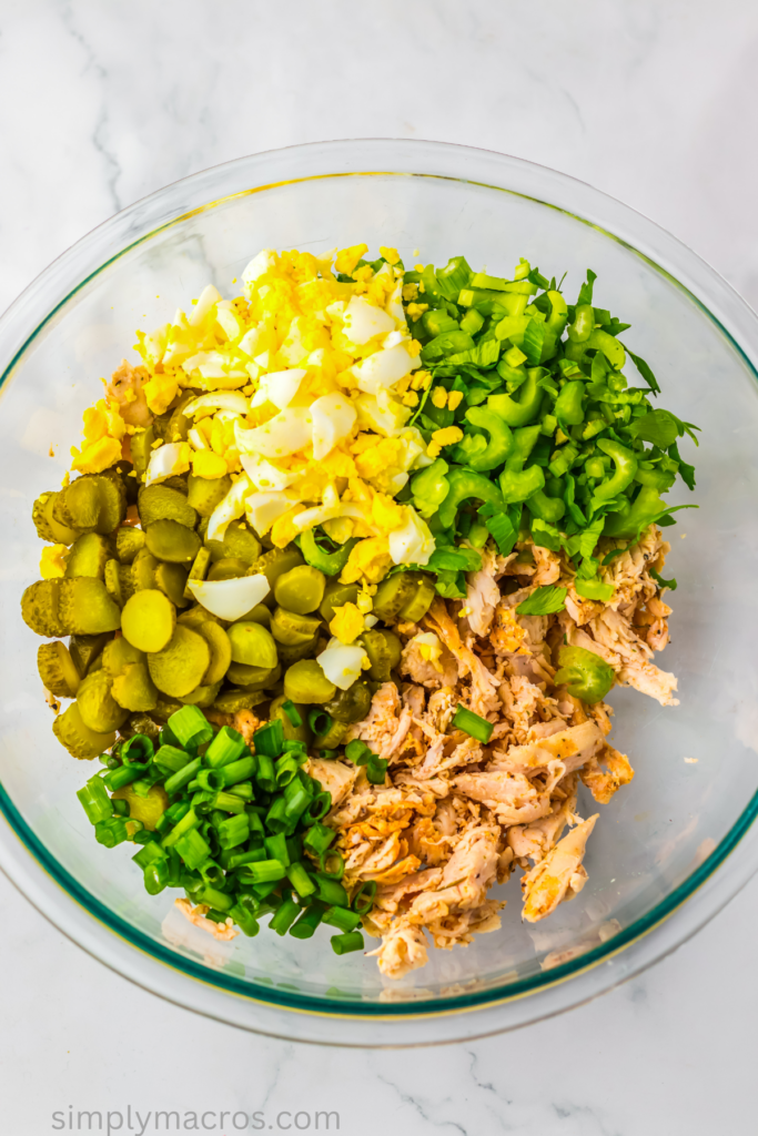Main ingredients for dill pickle chicken salad in a bowl, ready to combine. 