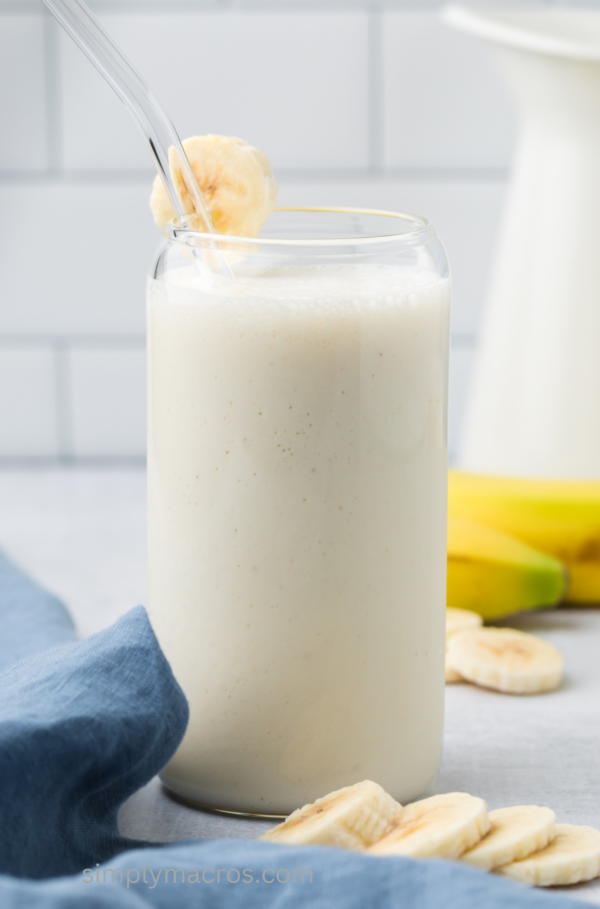 Easy banana smoothie in a glass with a slice of banana on the rim.
