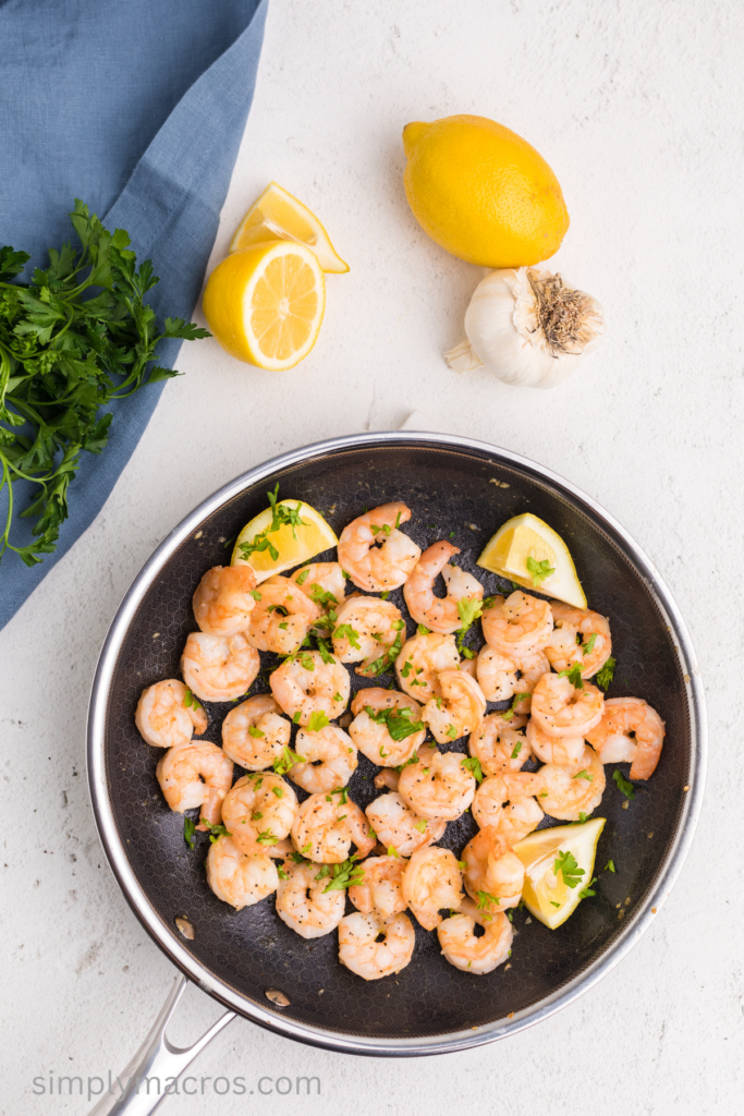 Freshly cooked shrimp with lemon and fresh parsley in a skillet. Ready to serve.