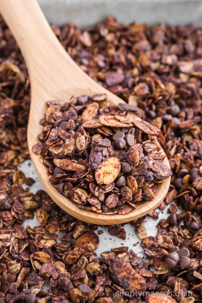 Close up photo of mocha almond gluten free granola on a wooden spoon, ready to scoop. 