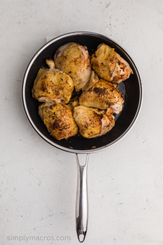 Chicken thighs in a skillet, lightly browned before placing them into the slow cooker. 