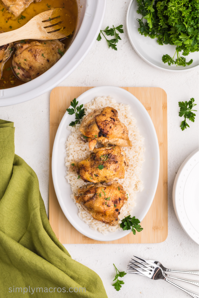 Slow cooker chicken thighs served on a plate of rice. 