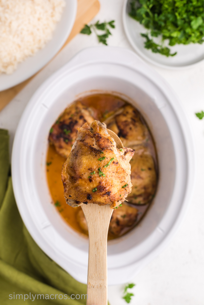 Spoon holding a crock pot chicken thigh, ready to serve. 