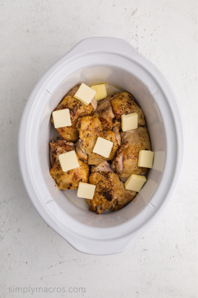 Chicken thighs in the crock pot seasoned and with butter on top. 