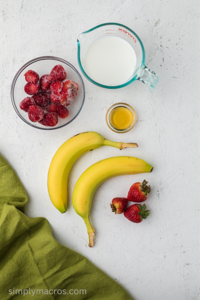 Ingredients needed to make a strawberry banana smoothie on a table top. 