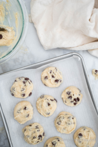 cottage cheese cookie dough scooped onto parchment paper on a baking sheet.