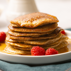 Stack of cottage cheese pancakes on a plate topped with syrup.