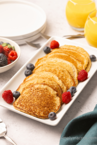 pancakes being served on a dish with fresh fruit.
