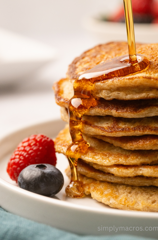 Close up of cottage cheese pancakes on a plate being drizzled with syrup.