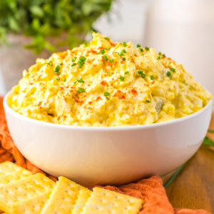 Deviled egg dip in a serving bowl with crackers to dip.