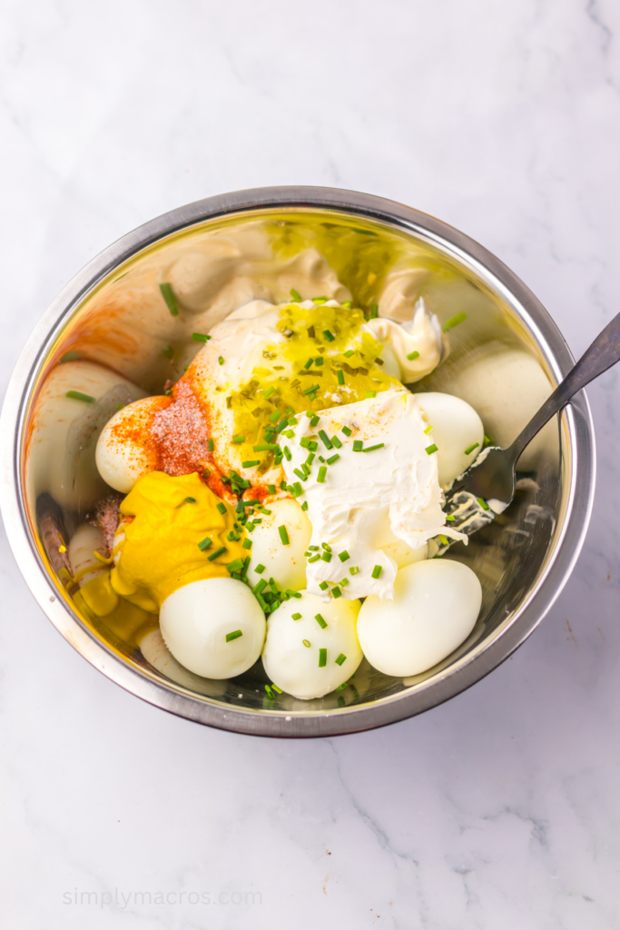 Ingredients added to a bowl to mix and combine to make deviled egg dip. 