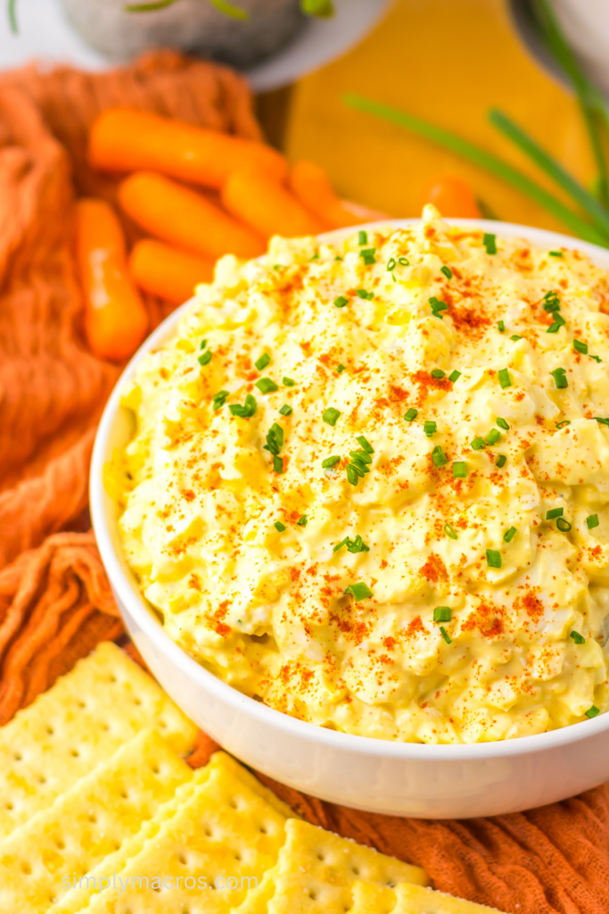 This deviled egg dip is served in a  bowl with paprika and chives sprinkled on top. 