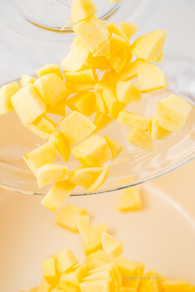 Diced and peeled apples being poured into a pan. 