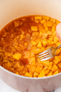 Applesauce being cooked and mashed with a fork.