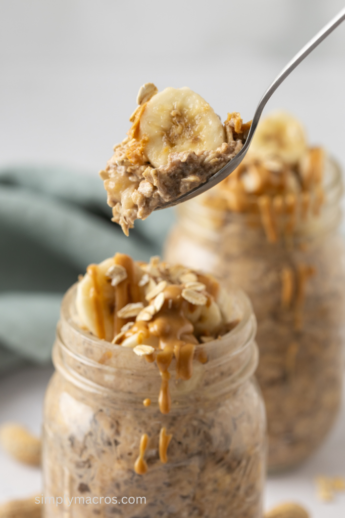 Close up of peanut butter and banana overnight oats in a jar with a bite on a spoon. 