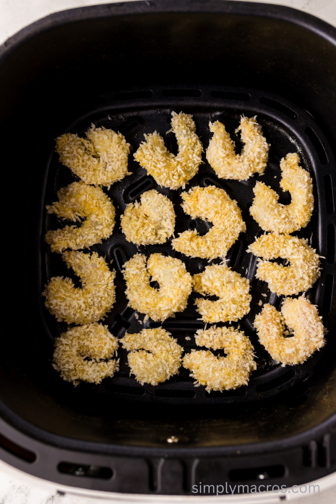 Coated shrimp in the basket of the air fryer.
