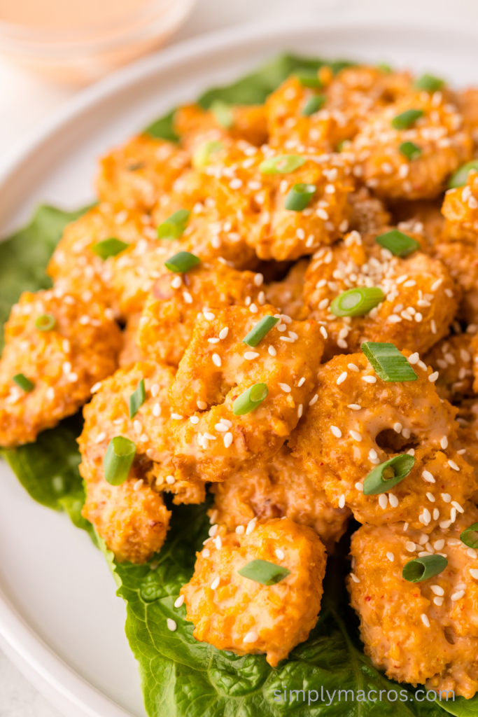 Air fryer bang bnag shrimp on a plate with sesame seeds and fresh onions on top.