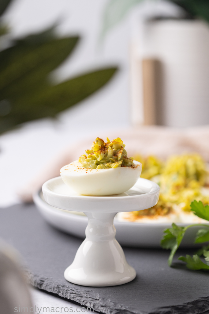 Photo of an avocado deviled egg on a pedestal, ready to eat.