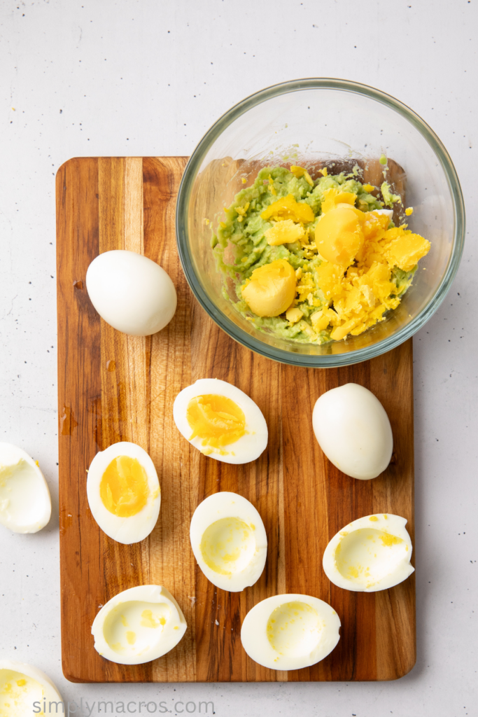 Egg yolks being removed and added to avocado in a bowl. 