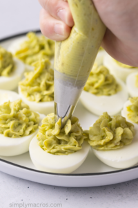 Eggs being piped with the avocado mixture.