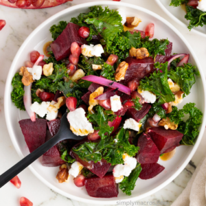 Beet and kale salad on a white plate with a fork in the middle.