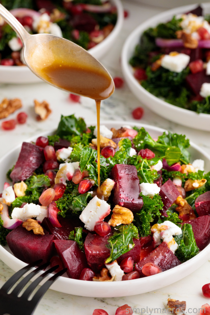 Dressing being drizzled over the beet and kale salad. 