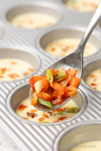 veggie mixture being scooped into the cottage cheese egg bites.