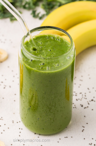 Green kale smoothie in a glass, ready to drink.