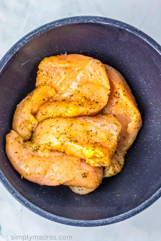 Seasoned chicken breasts in a large bowl. 