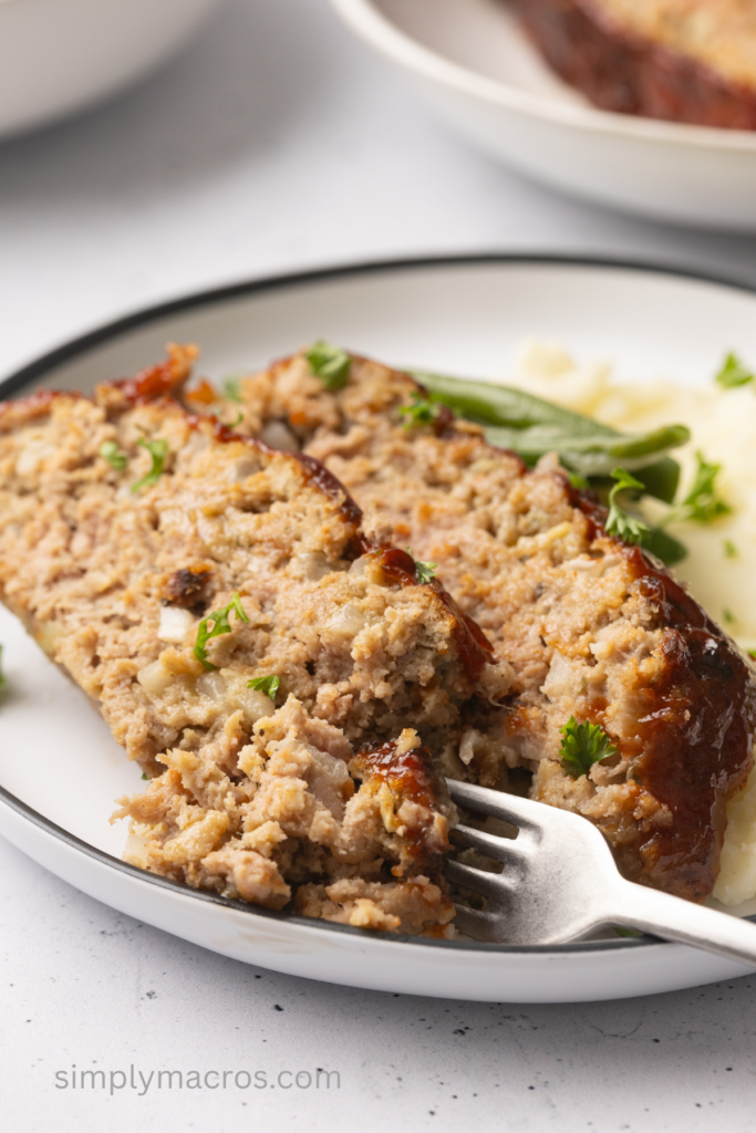 Close up of sliced turkey meatloaf with a fork removing a piece for a bite. 