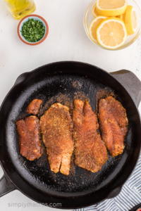Grouper fish filets cooking in a skillet.