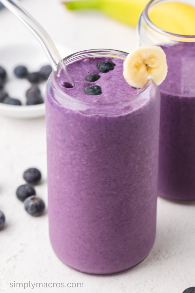 Close up angled shot of a banana blueberry smoothie in a glass. 
