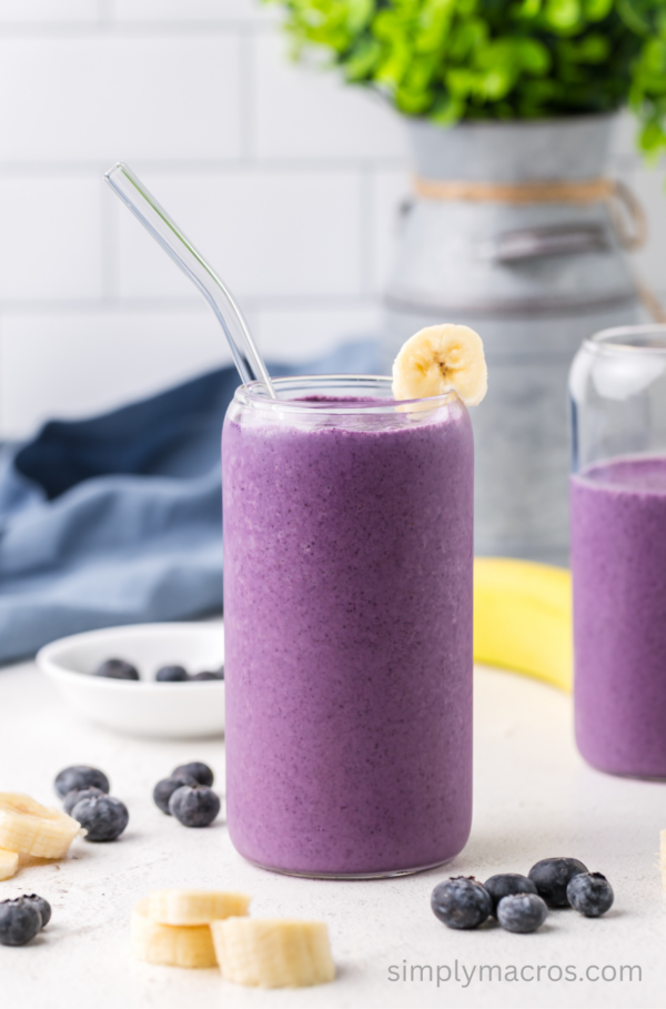Blueberry banana smoothie in a glass with a straw, ready to drink.