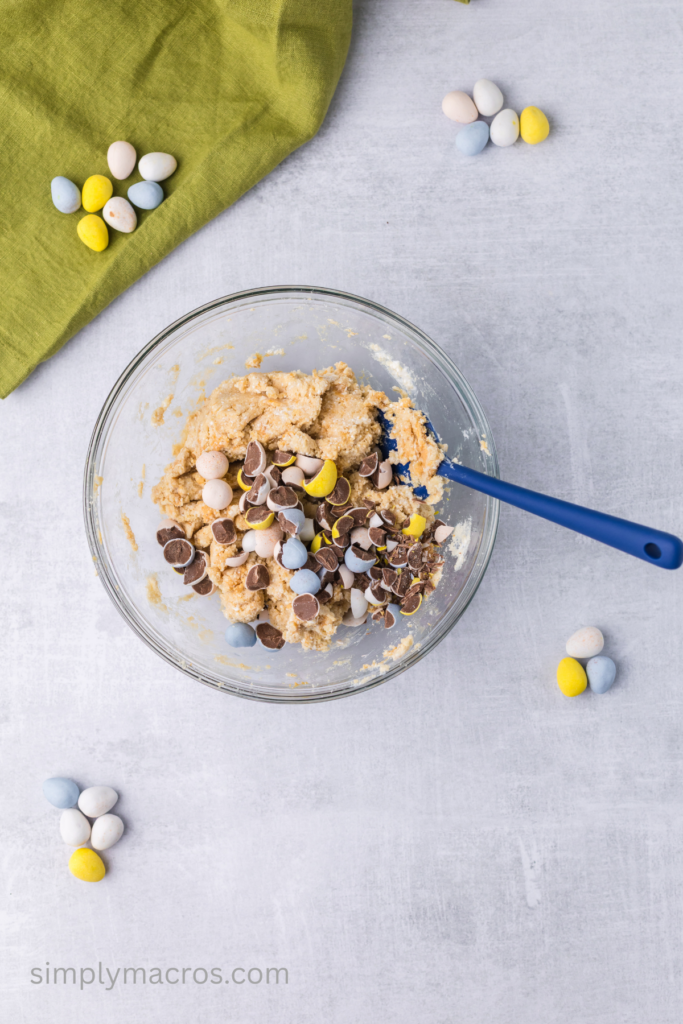 Chopped Cadbury eggs being folded into the protein cookie dough.
