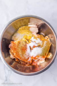 Chicken in a bowl covered in seasonings.