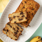 Sliced chocolate chip protein banana bread with a slice on top of the loaf.