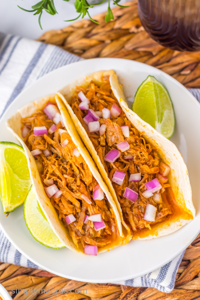 Overhead photo of sweet enchilada pork in tortillas topped with fresh diced onions. 