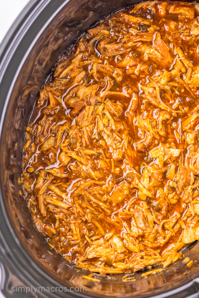Close up of sweet enchilada pork shredded in the bottom of the slow cooker. 