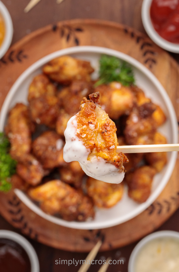 air fryer chicken bites on a plate, with a picture of a chicken bite dipped in sauce ready to eat.