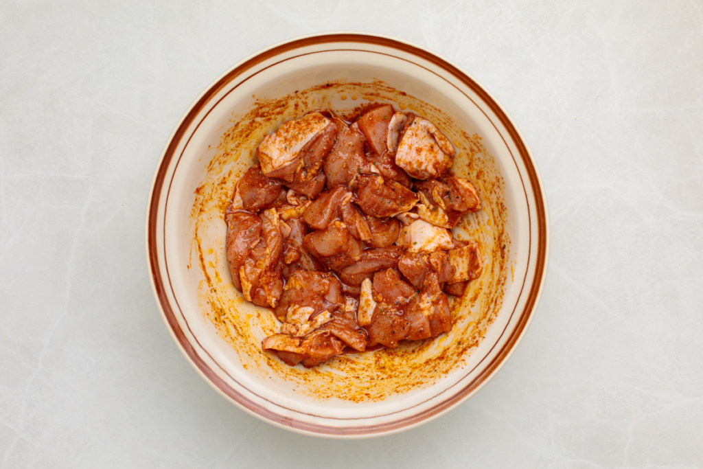 Spice blend poured over chicken pieces in a bowl and mixed well. 