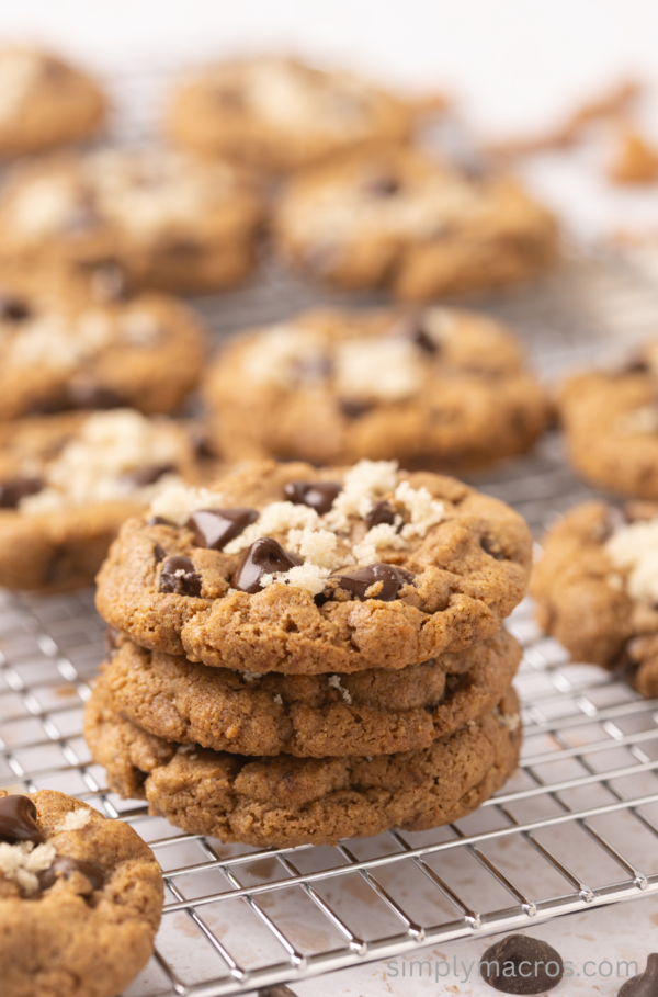 Close up of Almond Butter Chocolate Chip Cookies stacked on a cooling rack and surrounded by cookies.