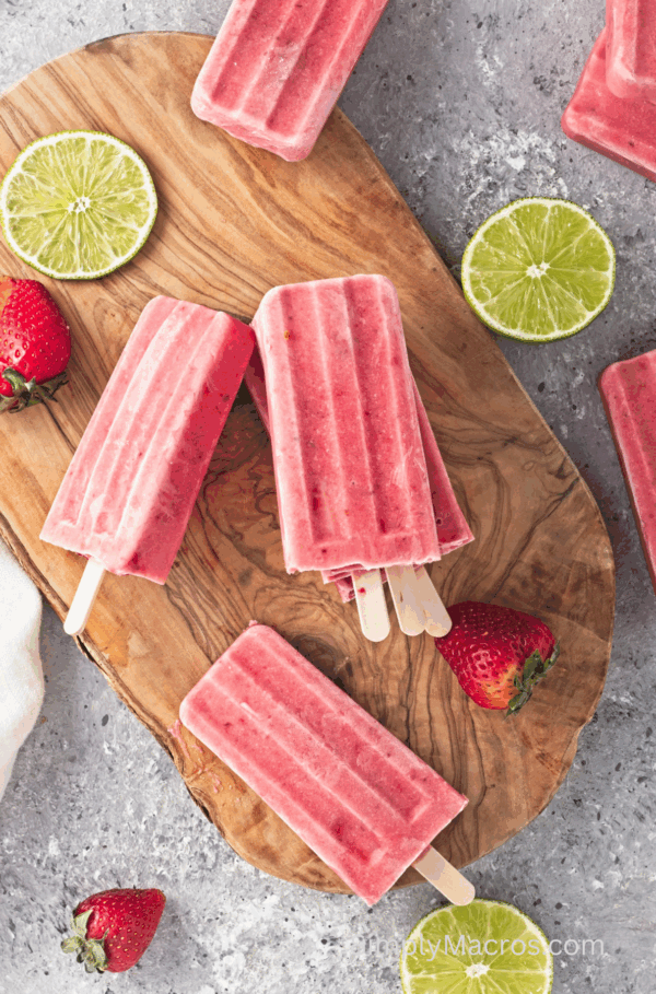 Creamy Strawberry Lime Popsicles on a cutting board.