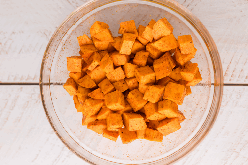 Peeled, diced, and seasoned sweet potatoes in a bowl. 