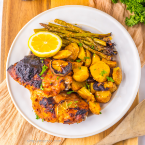 Overhead photo of roasted sheet plan lemon garlic chicken with potatoes and asparagus on a plate.