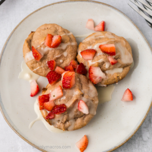 Overhead photo of strawberry cottage cheese muffins on a plate with fresh strawberries on top.