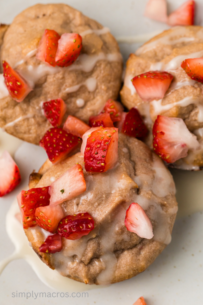 Strawberry cottage cheese muffins on a plate topped with a glaze and chopped strawberries.
