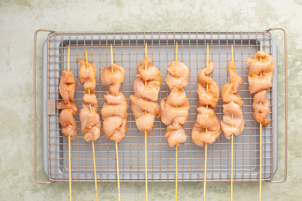Baking sheet with a wire rack on top and chicken skewers on the rack.