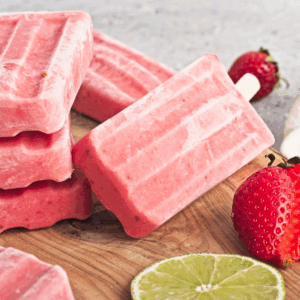 Close up of strawberry lime popsicles on a cutting board.